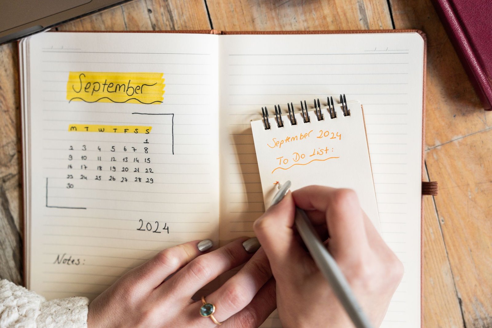 Person writing a to-do list beside a tablet while choosing a planner app