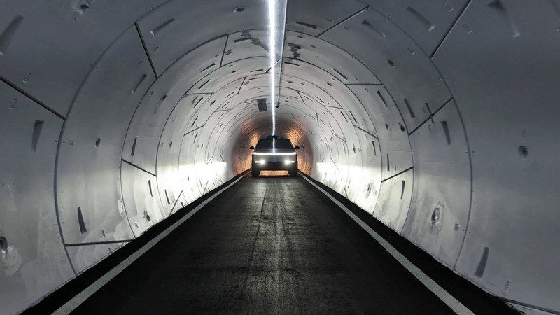 Cybertruck driving down a lit concrete-lined tunnel