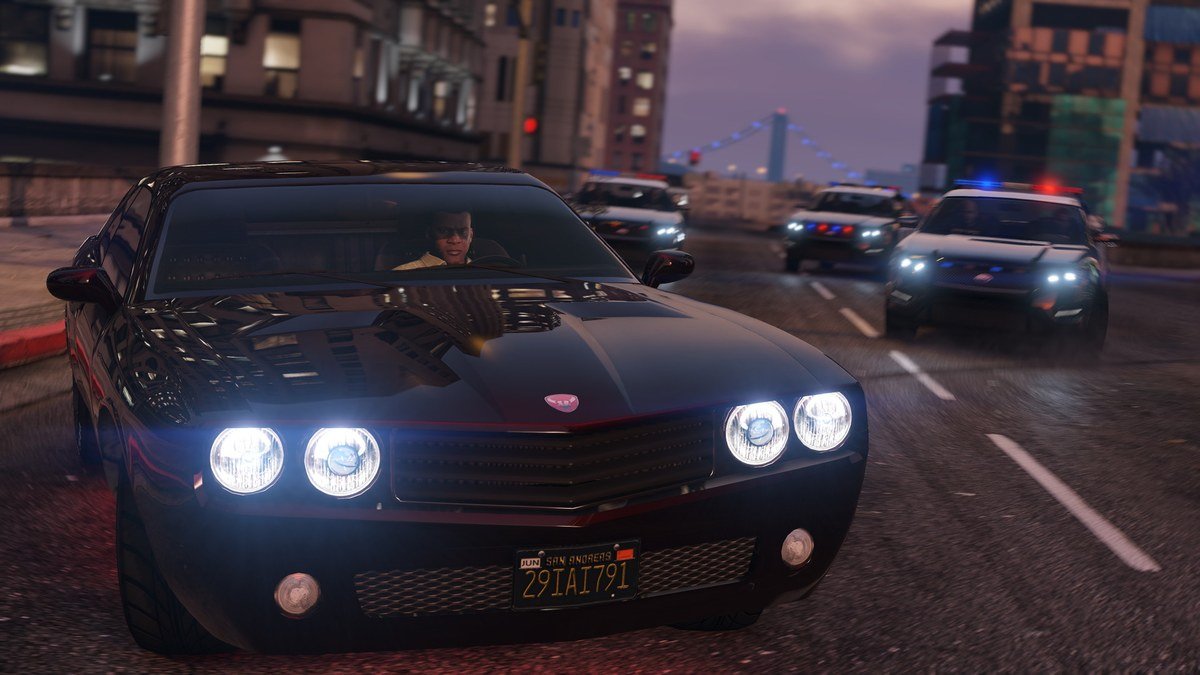 Black muscle car fleeing police cruisers down a city street at night in GTA 5