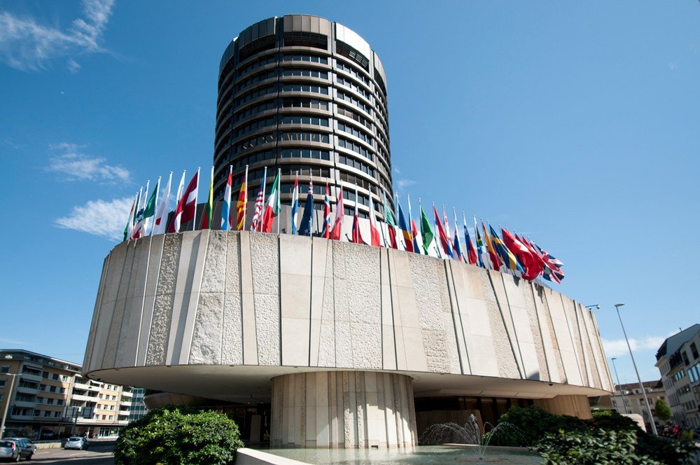 The circular Bank for International Settlements tower in Basel with member flags outside