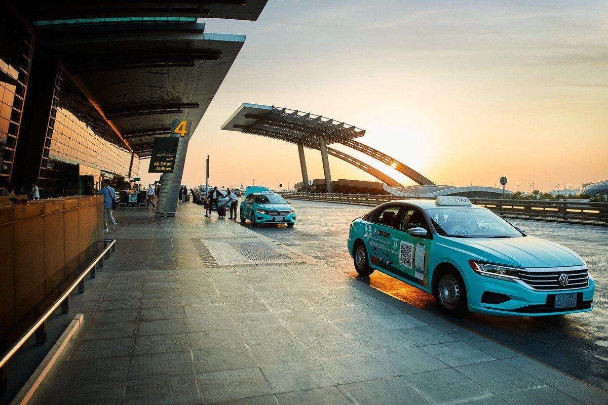 Taxi pulling up at a terminal entrance at Hamad International Airport in Doha at sunset