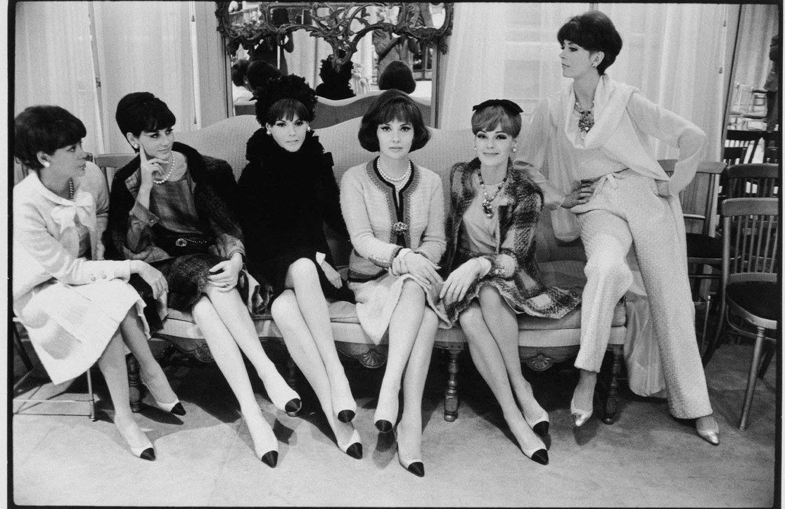 Black-and-white 1964 photograph of six women seated in a row on a sofa at CHANEL